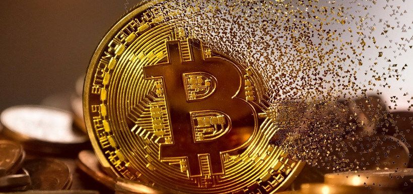 eine Bitcoin-Münze, die sich in viele Fragmente auflöst