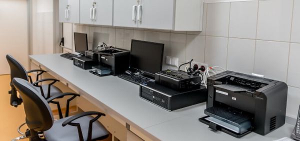PCs und Drucker stehen aufgereiht auf Labortischen