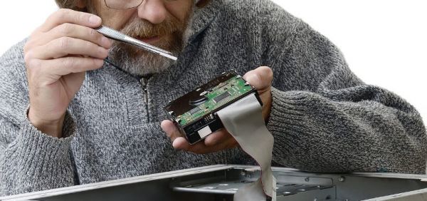Mann arbeitet an PC mit Pinzette