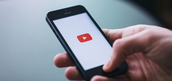 Smartphone wird in Hand gehalten und zeigt Youtube-Logo