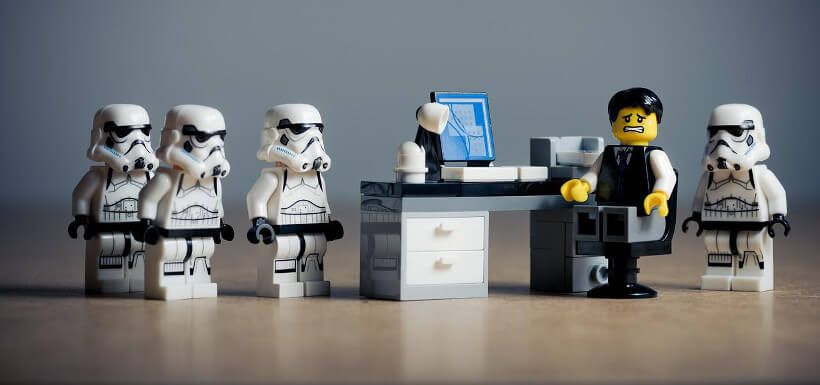 Lego-Szene: verzweifelter Mann am Schreibtisch, um ihn viele Stormtrooper