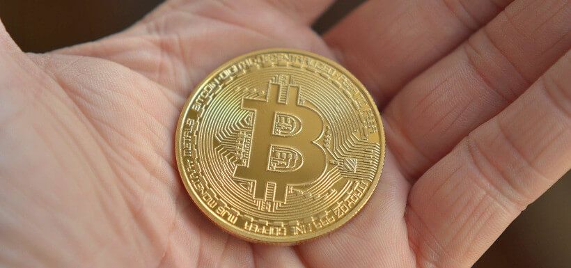 eine physische Bitcoin-Münze liegt in einer Handfläche