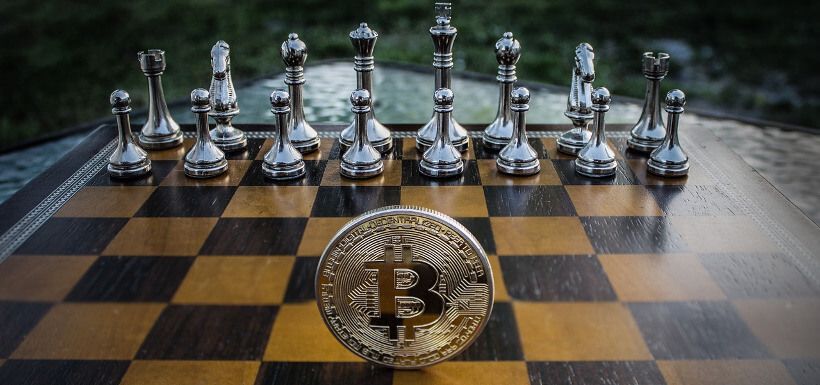 eine Bitcoin-Münze steht auf einem spielbereiten Schachbrett