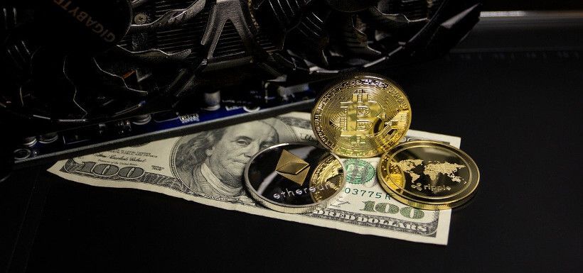drei Bitcoin-Münzen und ein Computerlüfter auf einem 100-Dollar-Schein