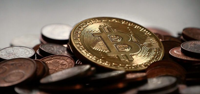 eine Bitcoin-Münze liegt auf Münzen von Fiatwährungen