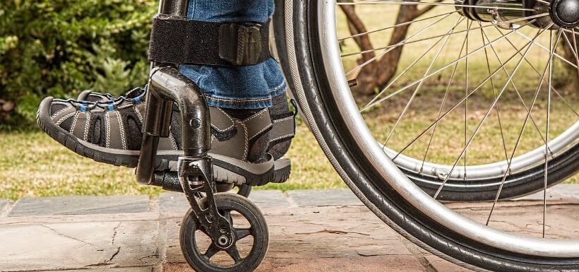 eine Person im Rollstuhl - Detail (Füße und Räder)